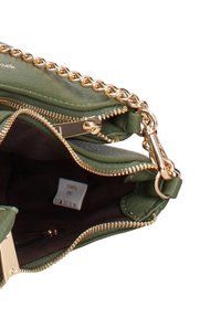 Borsa verde in PU con tracolla a catena dorata, chiusura con cerniera, fodera interna marrone e etichetta di cura visibile all'interno.