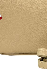 Beige leren handtas met een gestructureerd oppervlak, een korte band en een decoratieve rode accentaan de zijkant.