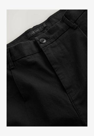 Pantalones negros con frente plano, cierre de botón único y detalles de costura sutiles. La tela tiene una textura suave y un acabado limpio.