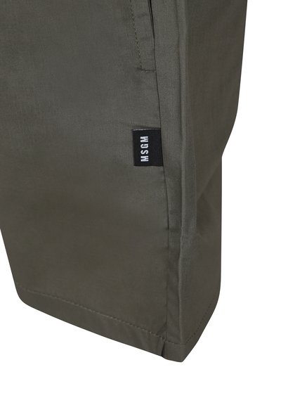 Pantaloni verde oliva realizzati in tessuto testurizzato, dotati di una tasca laterale e di un'etichetta nera con lettering bianco vicino all'orlo.