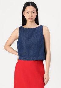 Korte denim top in donkerblauw, met een ronde halslijn en zonder mouwen, voorzien van een onbewerkte zoomafwerking. Gemaakt om over een rode rok te dragen.