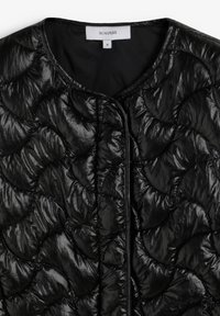 Chaqueta acolchada negra con un diseño acolchado de patrones redondeados, cuello redondo y abertura frontal sin cierres visibles.