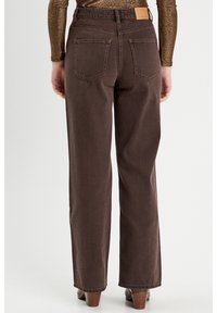 Bruine denim broek met een rechte pijp, voorzien van twee achterzakken, zichtbare stiksels en een tan leren label op de tailleband.