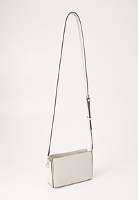 Borsa a tracolla bianca in pelle con bordi neri, forma rettangolare, tracolla regolabile e accessori in oro. Texture liscia con chiusura a zip.