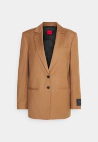 Braun taillierter Blazer mit Schalkragen, zwei schwarzen Knöpfen und Klapptaschen. Das Innenfutter besteht aus einem schwarz gemusterten Stoff und hat Branding an den Manschetten.