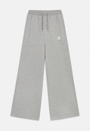 Pantalons de survêtement gris clair avec une coupe à jambes larges, taille élastique avec cordons de serrage, et un logo Adidas brodé en blanc sur le côté gauche. Texture douce.