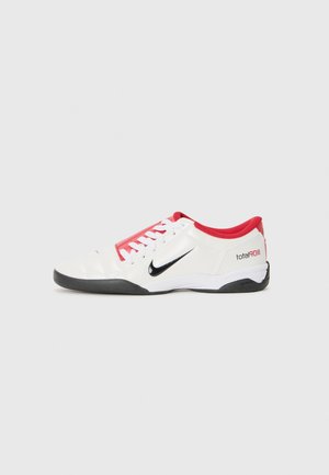 Chaussure de sport blanche avec des accents rouges, logo Swoosh noir et design texturé. Équipée de lacets blancs et d'une semelle noire. Le texte indique "total90".