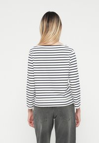 Maglietta a maniche lunghe con righe orizzontali blu navy e bianche, con scollatura rotonda e taglio dritto. Tessuto morbido con una finitura testurizzata.