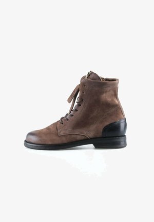 Bottine marron en daim à lacets avec un patch talon noir et une semelle basse empilée, vue de l’intérieur sur fond blanc.