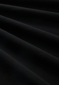 Sort stoff med en glatt tekstur, som har subtile folder og skygger, og viser en myk, matt overflate og dyp fargemetning.