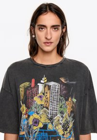 Prepadnuté tričko v antracitovej farbe s farebnou grafikou mestského horizontu a kvetov. Krátke rukávy, okrúhly výstrih, mäkká bavlnená textúra.