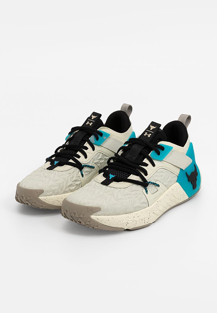 Zapatillas deportivas blancas con tejido texturizado, acentos negros, detalles en turquesa y una suela con patrón triangular. Cuentan con cordones ajustables y logo.