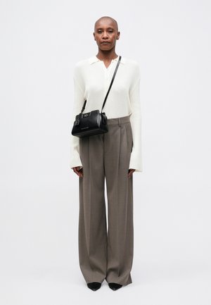 Maglione bianco a coste con colletto, pantaloni grigi a vita alta e a gamba larga, borsa nera con dettagli in argento e scarpe nere a punta.