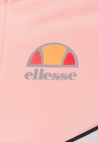 Light pink athletic fabric features a grey and orange ellesse logo, with rounded accents and ribbed texture. Notable color contrast.