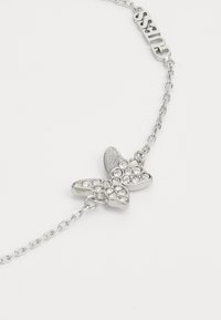 Silver butterfly bracelet with rhinestone embellishments, linked chain, and a "Guess" logo charm on the chain.