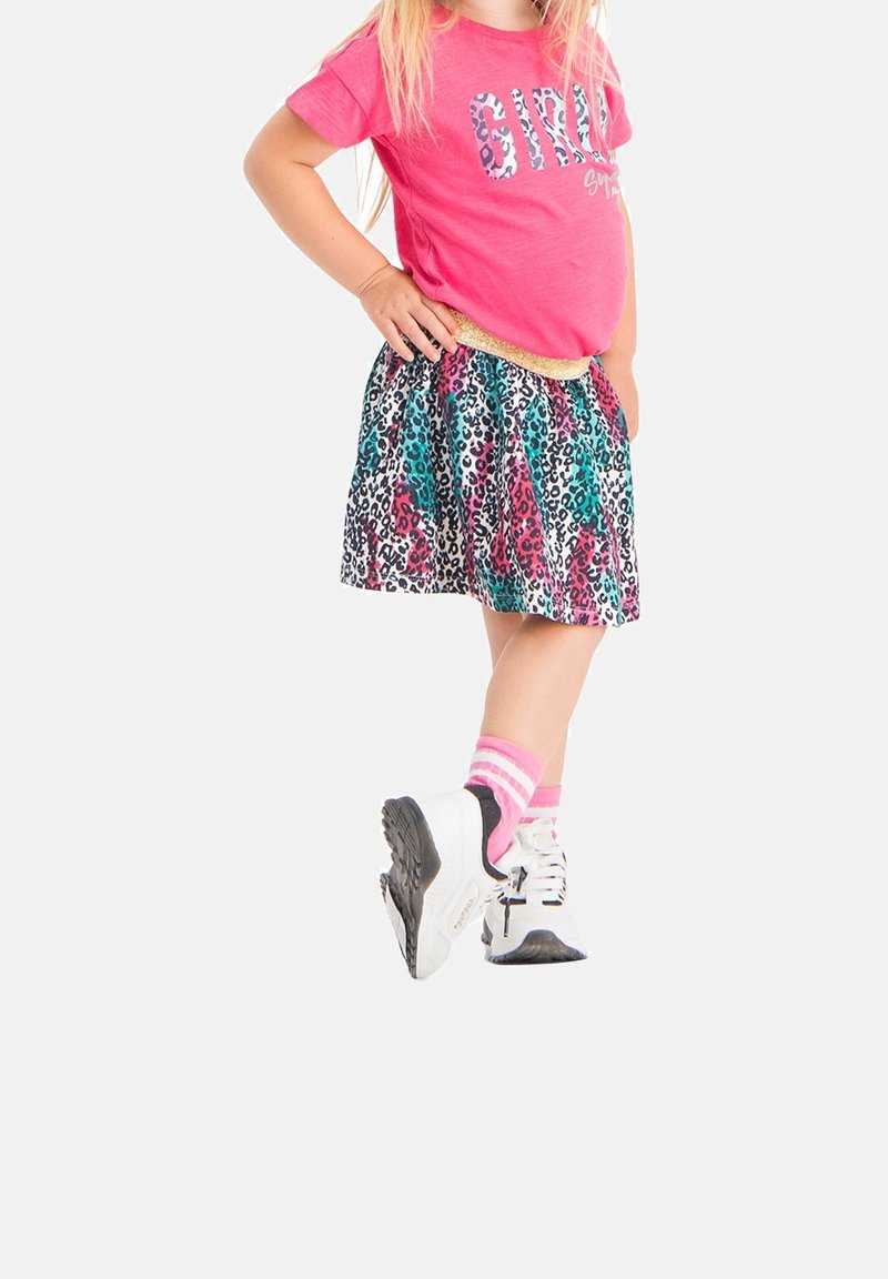 T-shirt rose avec "FILLE" en imprimé léopard, jupe colorée à motifs léopard, associée à des baskets blanches et des chaussettes rayées roses.