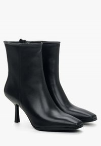 Czarne skórzane botki za kostkę z ostrym noskiem i 7 cm szpilką. Posiadają zamek błyskawiczny oraz gładką, błyszczącą fakturę.