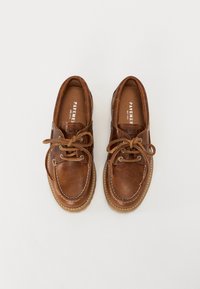 Chaussures en cuir marron avec lacets, forme arrondie, détails cousus et semelle texturée. À l'intérieur, elles possèdent une doublure en cuir avec logo.