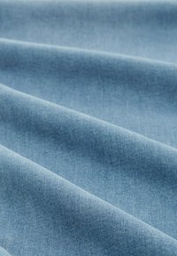 Svetlo modra denim tkanina z gladko teksturo; ima nežen gub in enakomeren vzorec tkanja, kar ustvarja mehko, privlačno podobo.