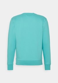 Sudadera larga de manga con puños y dobladillo acanalados en color turquesa, vista desde la parte posterior sobre un fondo blanco liso.