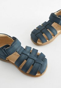Blaue Leder-Sandalen mit einem Riemen-Design und offenen Zehen und Fersen. Gepolsterte Innensohle und Gummisohle für Komfort und Flexibilität.