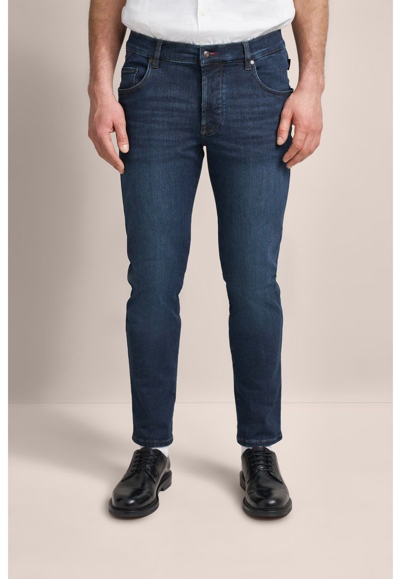 Ciemnoniebieskie dżinsy o slim fit, z pięcioma kieszeniami i subtelnymi detalami haftu. W połączeniu z czarnymi sznurowanymi butami.