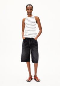 Weißes Tanktop mit schwarzen Streifen und einem kleinen roten Akzent, kombiniert mit knielangen schwarzen Jeansshorts und schwarzen Sandalen mit roten Details.