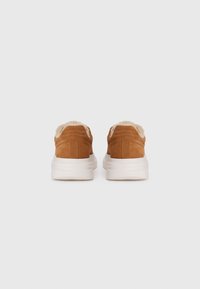 Brown suede sneakers with a soft beige lining, featuring a white chunky sole and subtle side stitching for added detail.