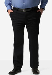 Pantaloni neri con una texture liscia, design a gamba dritta e tasche laterali, abbinati a una cintura nera e scarpe nere.