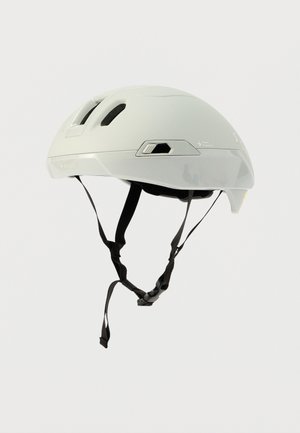Casco de ciclismo blanco con parte superior ventilada, correas negras ajustables y un diseño elegante y minimalista. Incluye detalles de seguridad en los laterales.