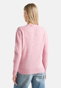 Różowy sweter z dzianiny o fakturowanym wykończeniu, z prążkowanymi mankietami i dołem. Projekt charakteryzuje się klasycznym okrągłym dekoltem oraz luźnym krojem.
