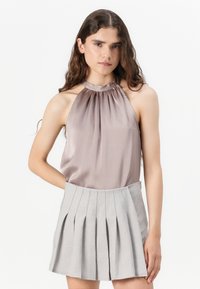 Ärmelloses, beiges Satin-Top mit gerafftetem Halsauschnitt, kombiniert mit einem hellgrauen, plissierten Minirock mit glattem Bund.