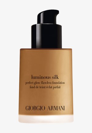 Goldene Glasflasche mit einem schwarzen Pumpkopf. Schwarzer Text lautet "luminous silk perfect glow flawless foundation" und "GIORGIO ARMANI."