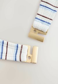 Curea din material textil alb cu dungi albastre și maro, cu capete de cataramă dreptunghiulare aurii, pe un fundal deschis.