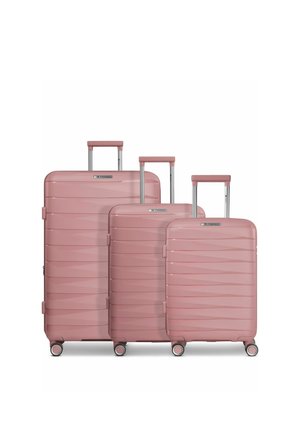 Tre valigie rigide rosa di diverse dimensioni sono in piedi, ciascuna con quattro ruote e una maniglia telescopica estesa.