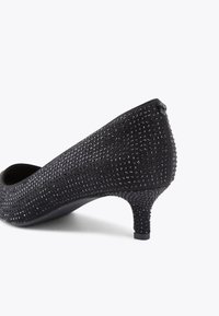 Scarpe nere con tacco alto e superficie testurizzata adornata da piccoli strass, caratterizzate da un tacco affusolato e una punta arrotondata.