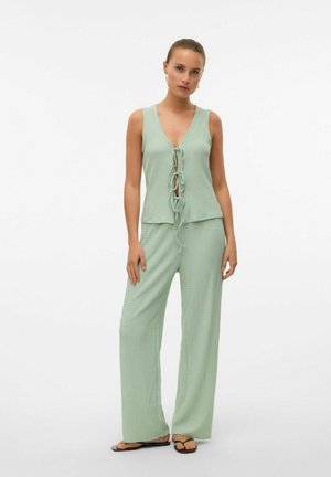 Haut sans manches vert clair avec un col en V et un détail de lien à l'avant, associé à un pantalon large texturé, le tout dans un tissu assorti.