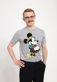 Šedé bavlněné tričko s barevným motivem kreslené postavičky s květinovou korunou, doplněné černými kalhotami a černým páskem.