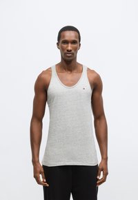 Maiou gri deschis din material moale, cu decolteu rotund și bretele late. Detaliu mic cu logo pe piept.