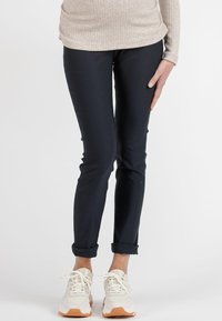 Navy blue, slim-fit pants with a smooth texture. Rolled cuffs and a minimalist design. Paired with light-colored sneakers.