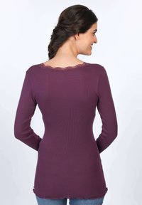 Langärmliges lila Oberteil aus geripptem Stoff, mit einem gewellten Spitzenkragen und -saum, in körperbetontem Schnitt.