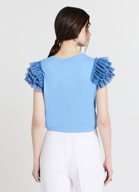 T-shirt bleu en tissu doux, avec des accents bleus froncés sur les épaules. Vue de dos montrant une coupe décontractée avec un col rond.