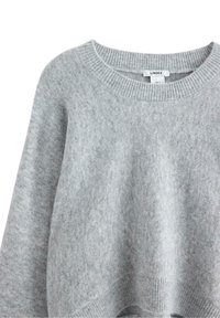 Grå tröja med rund halsringning, med ribbade muddar och nederkant. Etiketten visar varumärket "LINDEX" och storleken "EUR S." Mjuk textur.