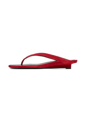 Sandalo piatto in suede rosso con cinturino a infradito e tacco leggermente rialzato, mostrato di profilo su sfondo bianco.