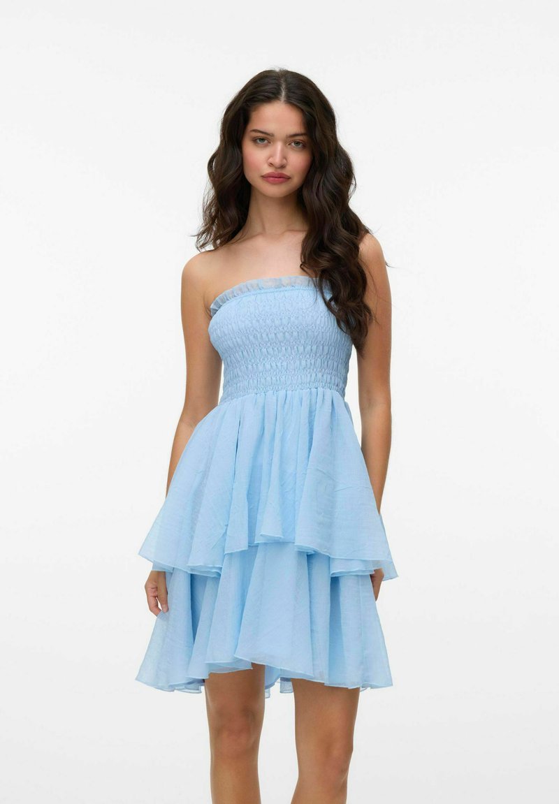 Zila bezsēde kleita ar smockota korpusa, slāņota volāna svārkiem un vieglas auduma, ar nedaudz caurspīdīgu augšējo malu.