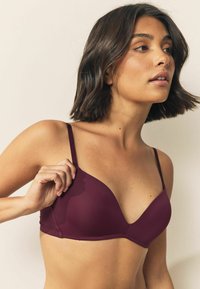 Bordeaux, naadloze bralette met verstelbare dunne bandjes, featuring een diepe V-hals en een gladde textuur. Geen versieringen of padding.