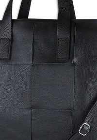 Zwarte leren handtas met een gestructureerd geweven ontwerp, dubbele handvatten en een verstelbare band met zilveren accenten.