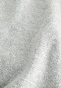 Tissu gris clair avec une texture douce, présentant un motif tricoté subtil. Le matériau semble légèrement brossé, offrant un aspect chaleureux.