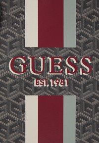 Musta teksturoidun taustan geometrinen kuvio. Sisältää valkoiset ja lihavoidut punaiset kirjaimet, jotka muodostavat sanat "GUESS" ja "EST. 1981," sekä pystysuorat raidat punaisena ja vaaleansinisenä.