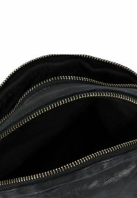 Bolso de cuero negro con tres compartimentos con cremallera. Presenta cremalleras en tono dorado y una textura suave y mate en el forro interior.